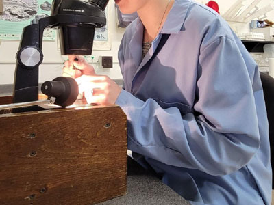 image of employee at bench looking through microscope